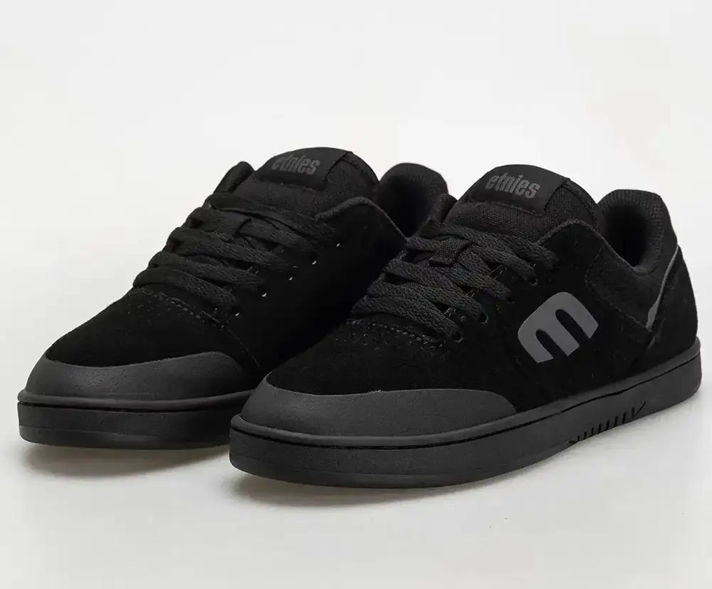 A pair of black low-top skate shoes with a matte finish, featuring a prominent stylized 'e' logo on the side and tongue, photographed on a light gray studio background.