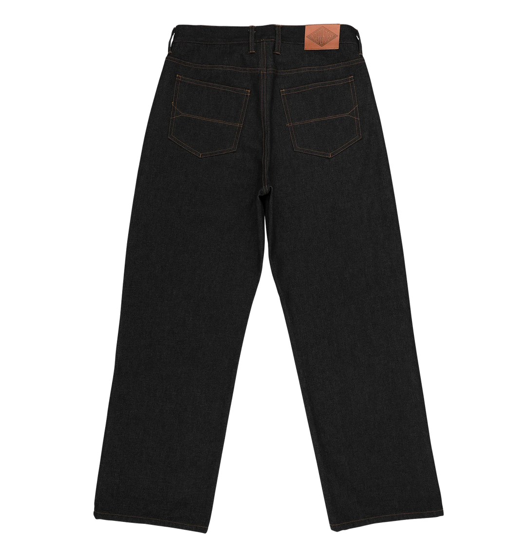Rear view of dark indigo denim jeans with contrast tan stitching and a brown leather patch on the back waistband, shown on a plain white background.