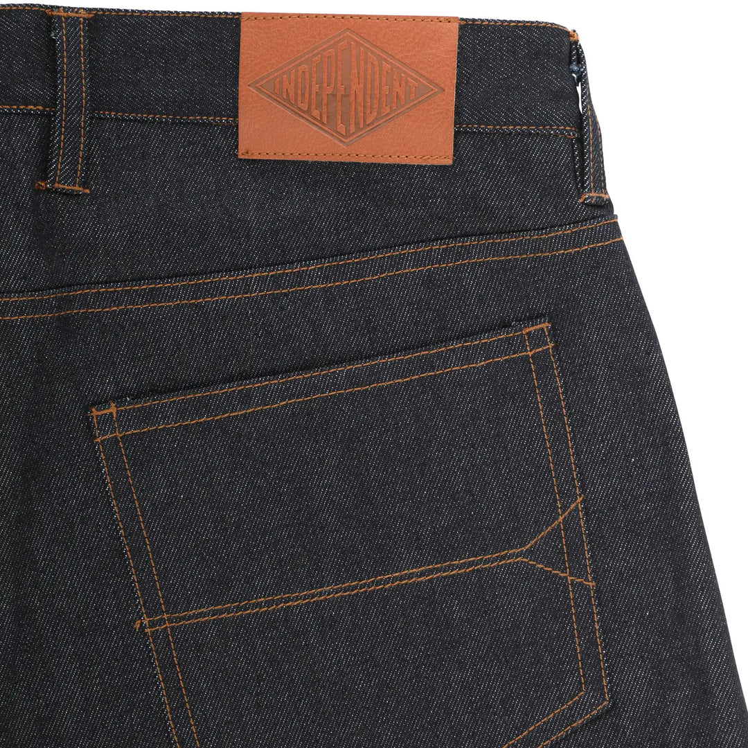 Close-up of the back waistband and pocket of dark indigo denim jeans, showing orange contrast stitching and a brown leather patch with the brand name 'KODAGAWA' on the waistband.