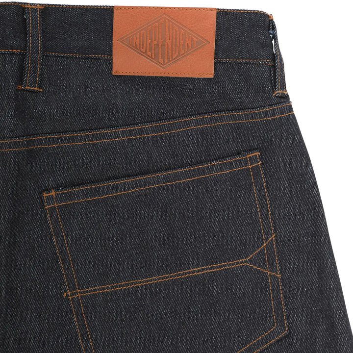 Close-up of the back waistband and pocket of dark indigo denim jeans, showing orange contrast stitching and a brown leather patch with the brand name 'KODAGAWA' on the waistband.