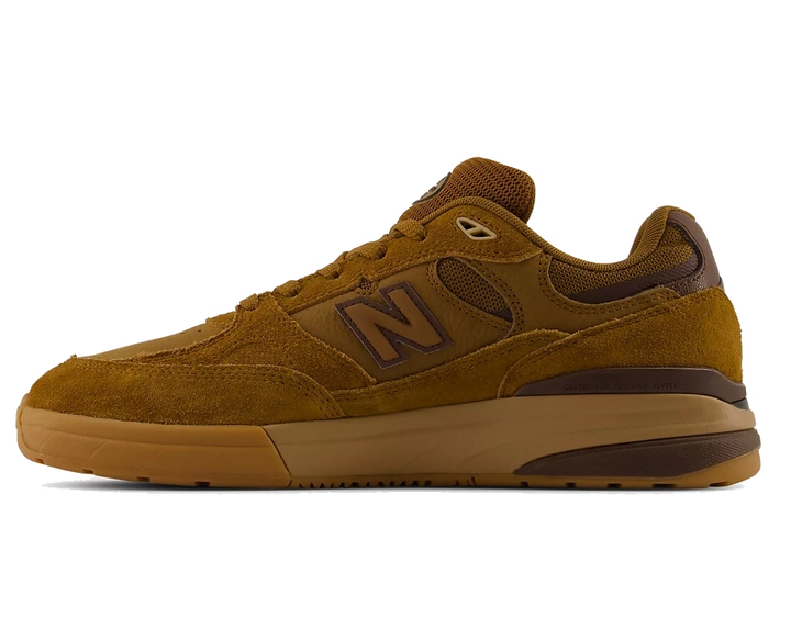 A single New Balance sneaker in a warm brown suede and mesh upper with a matching gum sole, shown in a side profile on a white background.