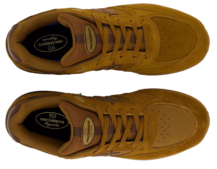 A pair of New Balance 935 sneakers in a monochromatic mustard brown colorway, shown from a top-down view on a solid white background.