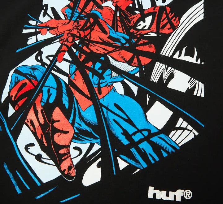 A close-up of a black graphic t-shirt featuring a stylized, comic-book style illustration of Spider-Man in red and blue, with blue speed lines and a white 'huf®' logo on the bottom right.
