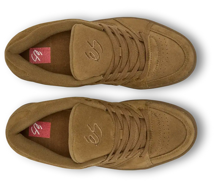 A pair of low-top suede sneakers in a warm tan-brown color, shown from a top-down view on a white background with a soft drop shadow. The shoes feature matching brown laces, a stitched logo on the tongue, and a red insole label.