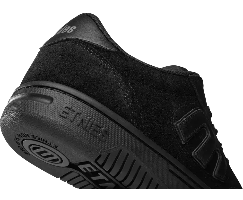 A close-up studio shot of a black Etnies skate shoe, showing the heel, side profile, and textured rubber sole on a plain white background.