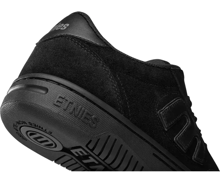 A close-up studio shot of a black Etnies skate shoe, showing the heel, side profile, and textured rubber sole on a plain white background.