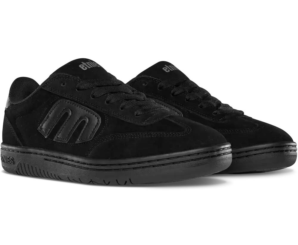 A pair of black low-top skate shoes from Elixir, featuring a suede and leather mix, tonal black logo detailing, and black laces, shown against a plain white background.