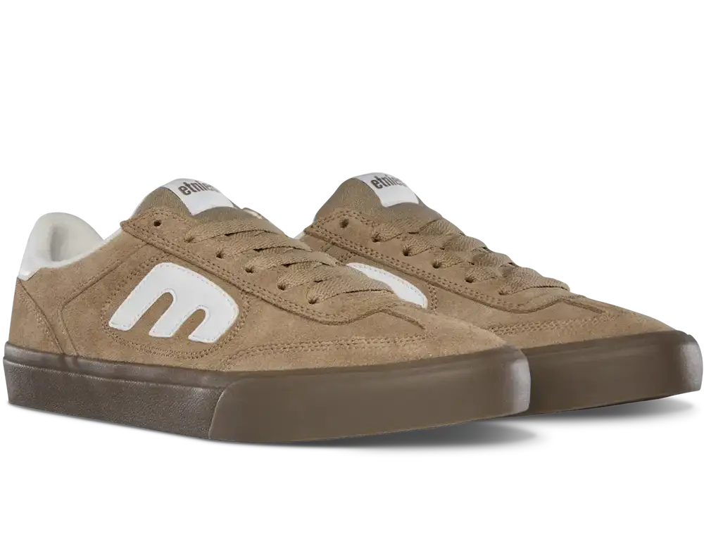 A pair of low-top suede sneakers in a warm tan color, featuring a prominent white stylized 'm' logo on the side, white laces, and a dark brown rubber sole, shown against a plain white background.