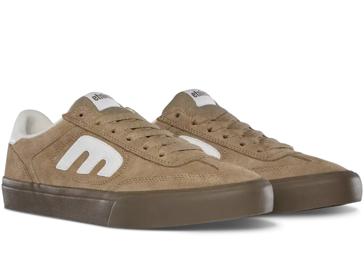 A pair of low-top suede sneakers in a warm tan color, featuring a prominent white stylized 'm' logo on the side, white laces, and a dark brown rubber sole, shown against a plain white background.