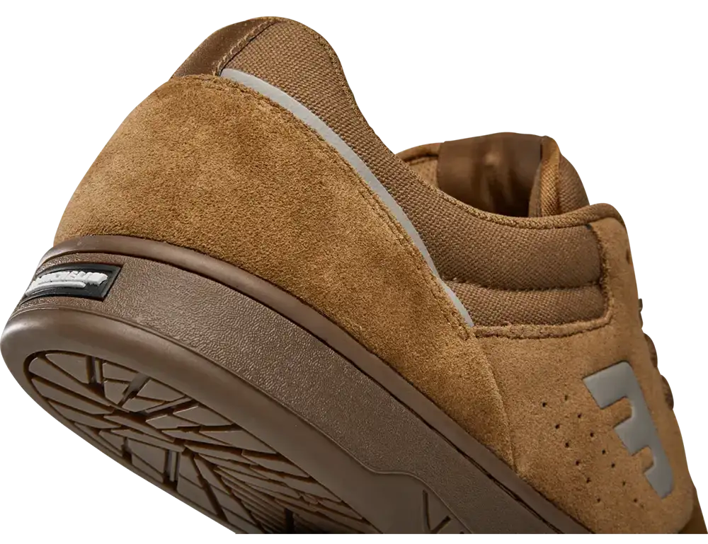Close-up of a brown suede and canvas sneaker showing the heel, side profile, and textured sole on a white background.