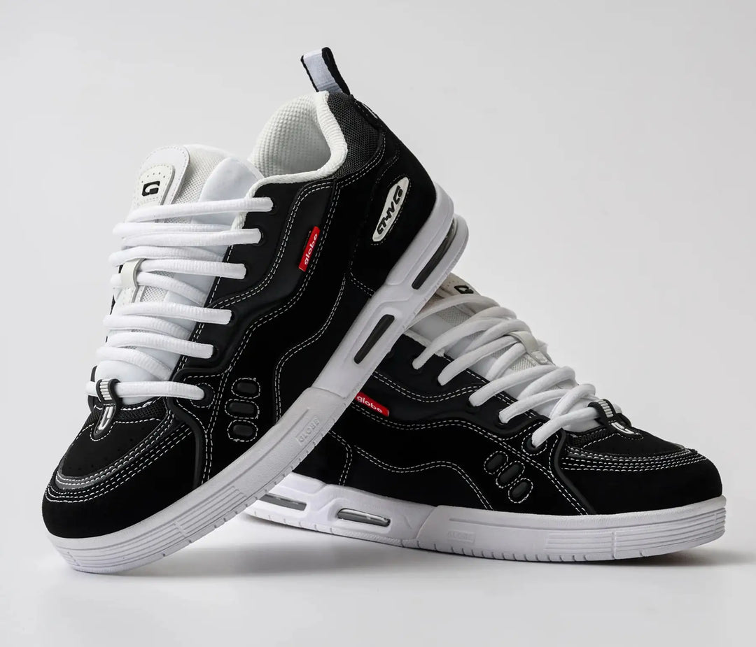Black and white sneakers with visible branding on a light gray background