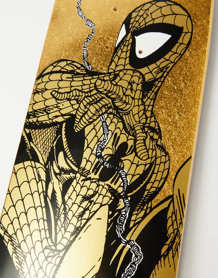 A close-up of a skateboard deck featuring a comic-style illustration of Spider-Man in black and gold, with a glittery gold background and white eye details.