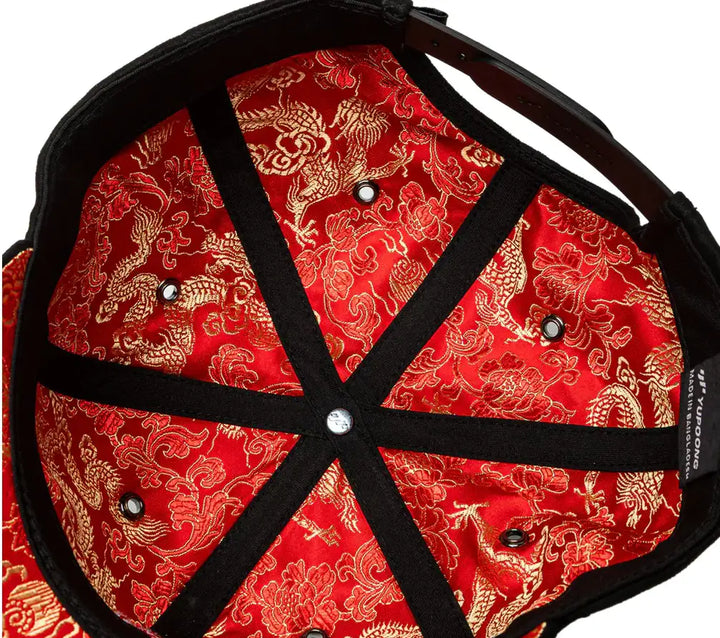 Red cap with gold dragon pattern and black straps on a white background