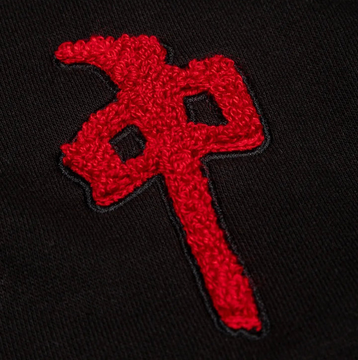 A close-up of a textured red embroidered RDS patch on a black knit fabric background.