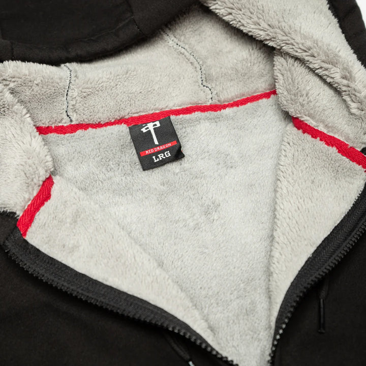 Close-up of a black zippered jacket interior with a soft light gray fleece lining and red contrast stitching. A small black neck label reads LRG.