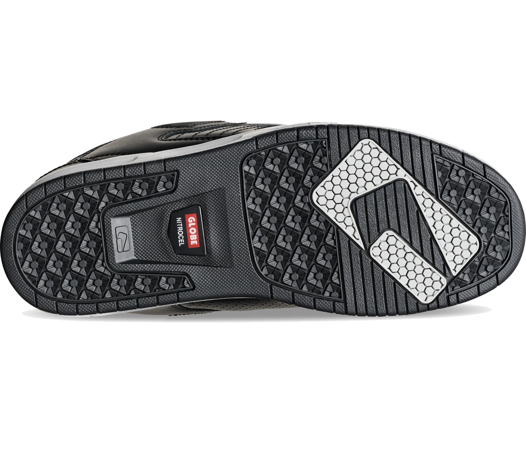 A close-up of a shoe's black textured outsole, showing the G-1000 grip pattern and a white reflective logo on the heel.